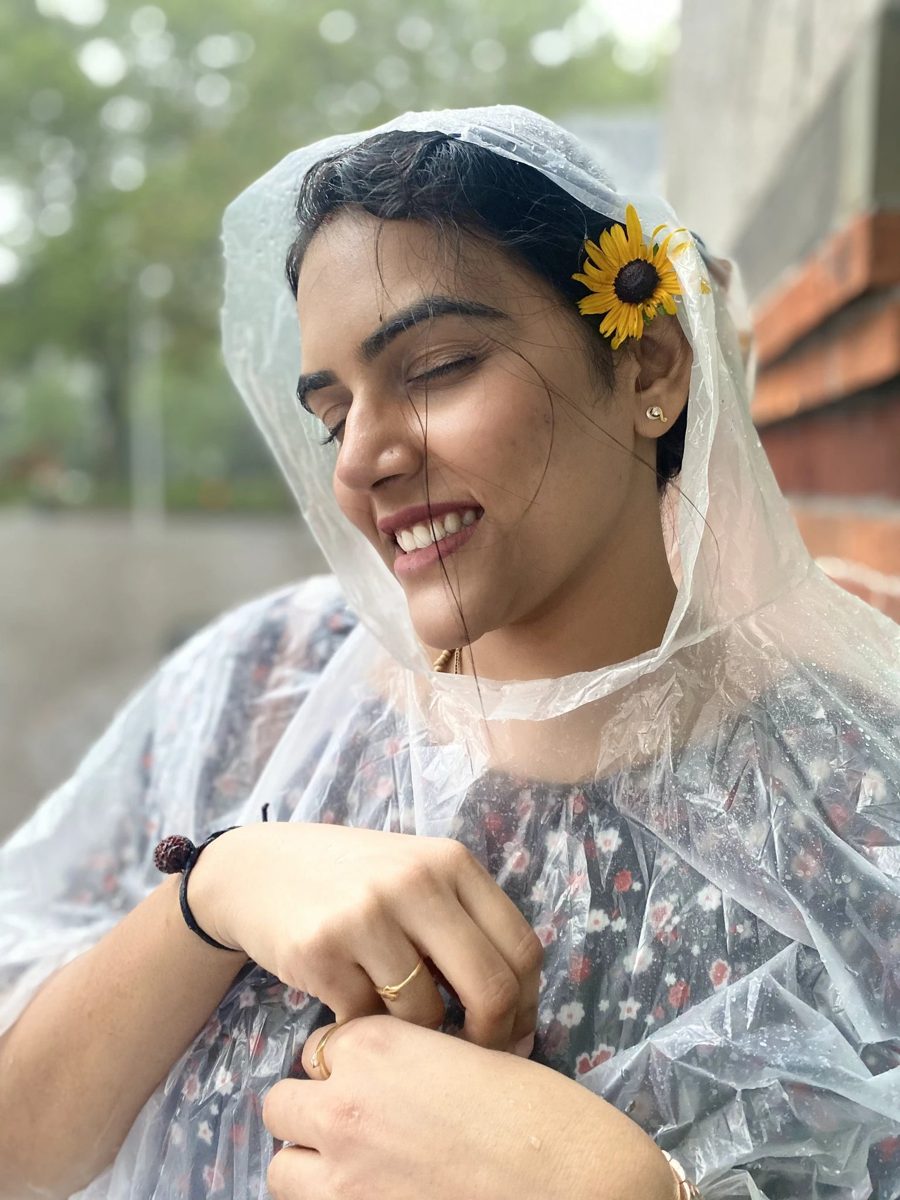Shivani laughing in a clear rain poncho with a flower in her hair