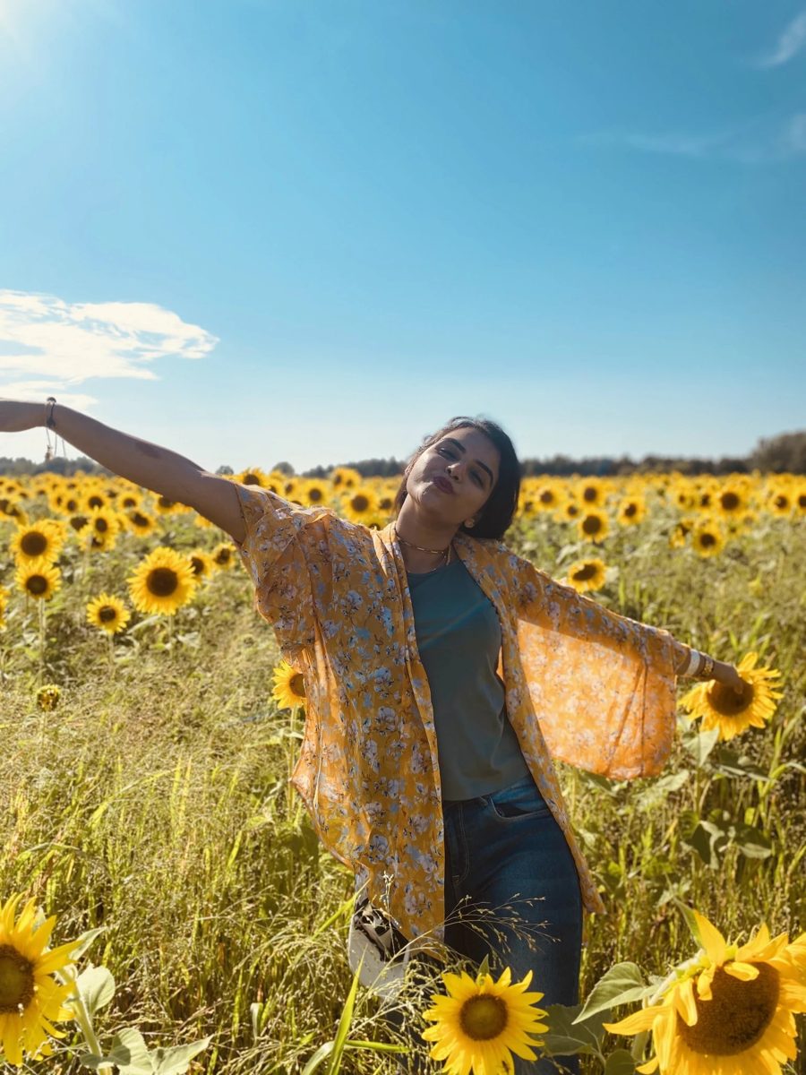 Shivani with arms outstretched in a sunflower field